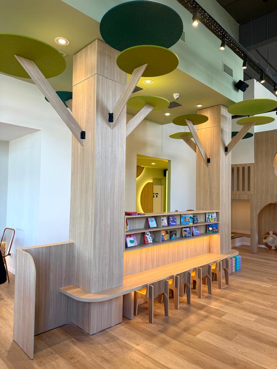 Rincón de lectura con árbol de madera y sillitas